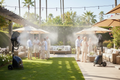 Outdoor evening event with guests, black misting systems for events cooling a dance floor, string lights, pool, and city skyl