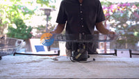 Person holding a large metal grill outdoors with a blurred background