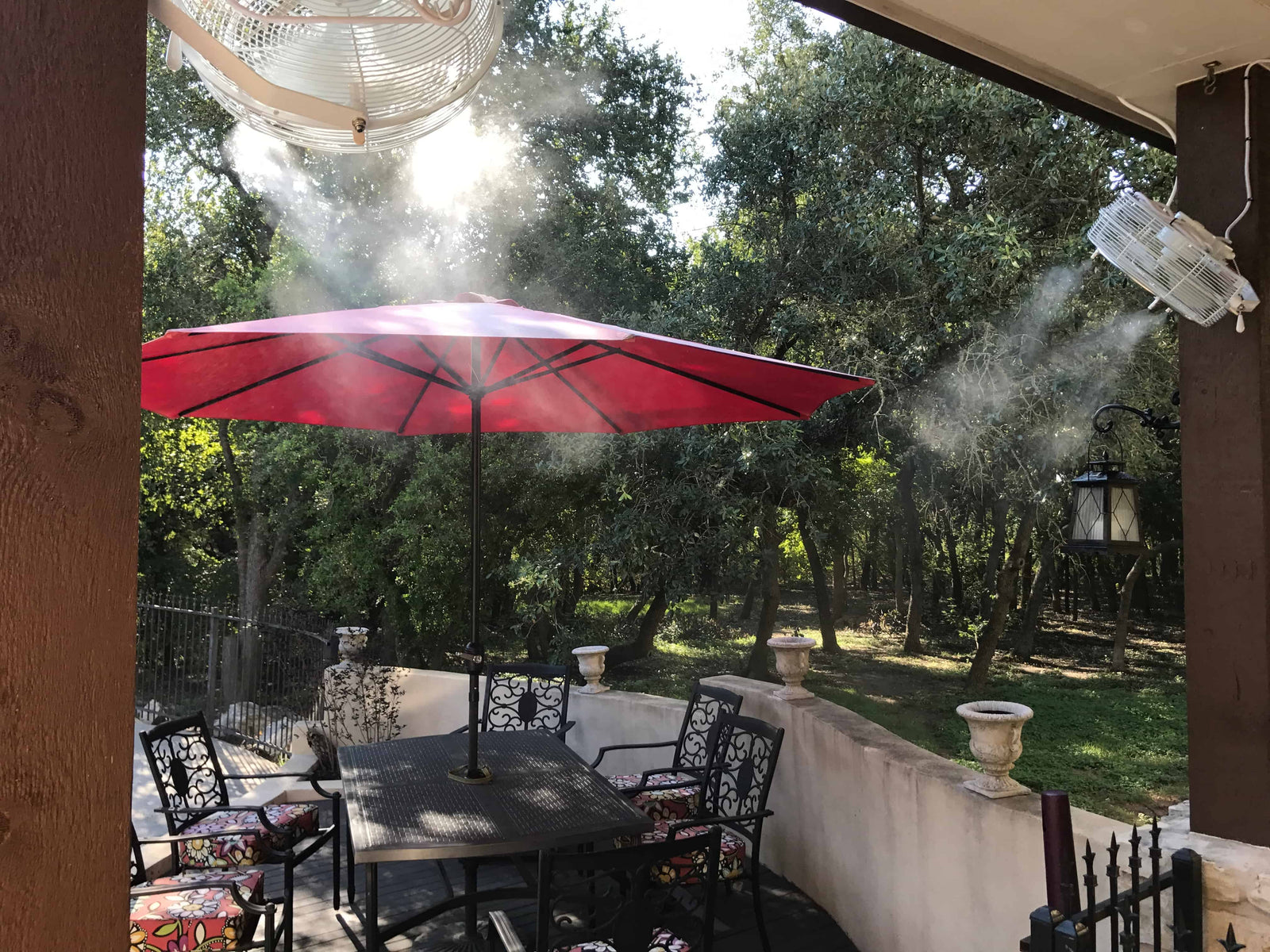 Outdoor patio with red umbrella, table, and chairs on a sunny day.