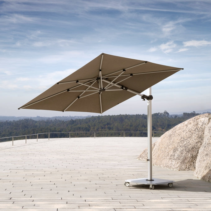 Beige patio umbrella on a stand with a scenic background
