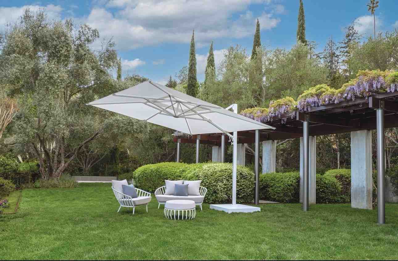 Outdoor patio with a large umbrella, chairs, and a garden setting.