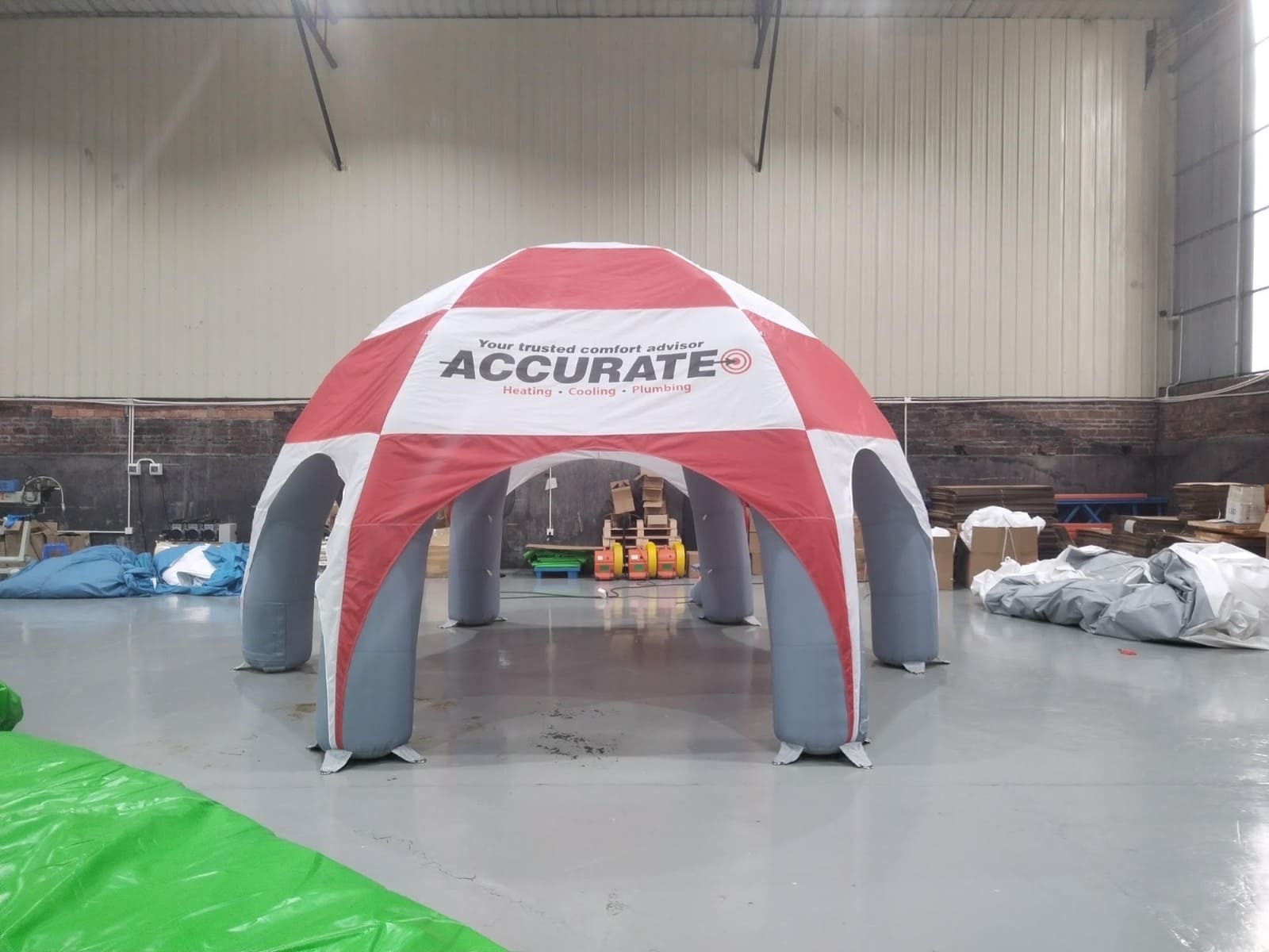 Red and white inflatable tent with 'Accurate' branding in a warehouse setting