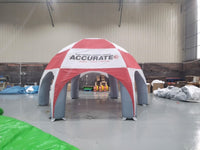 Red and white inflatable tent with 'Accurate' branding in a warehouse setting