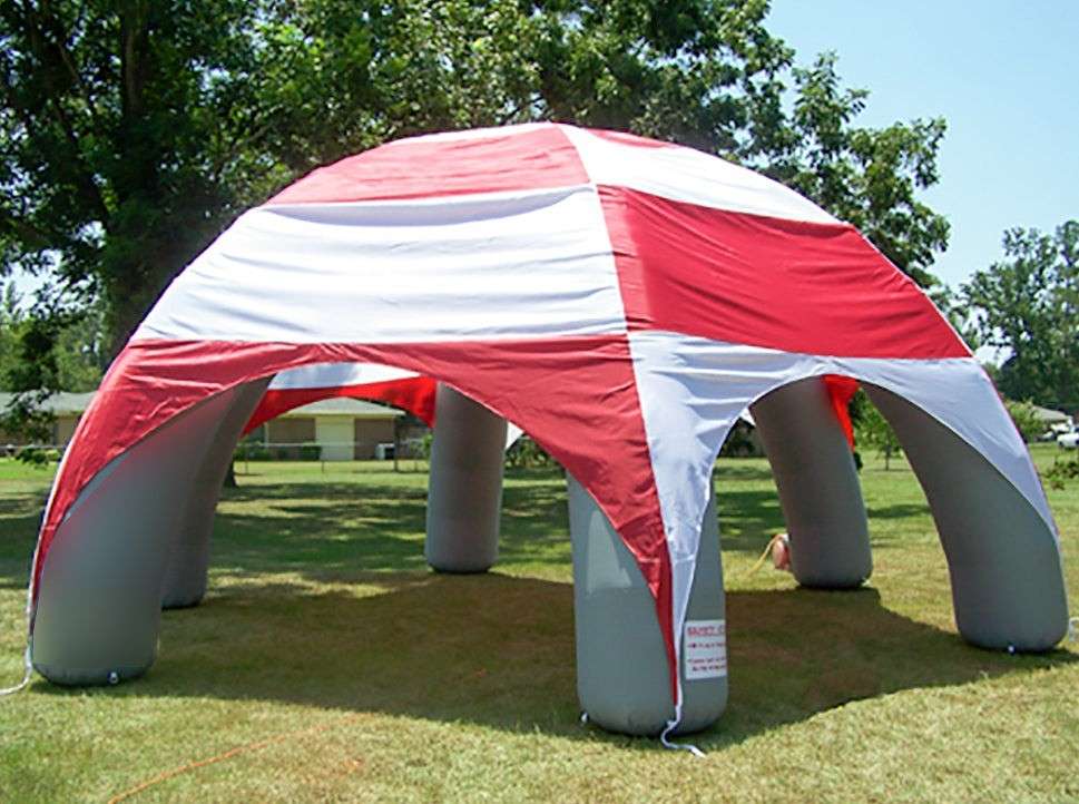 Inflatable tent with red and white striped canopy on grassy field
