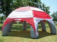 Inflatable tent with red and white striped canopy on grassy field