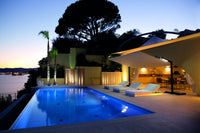 Evening view of a pool area with lounge chairs and outdoor furniture.