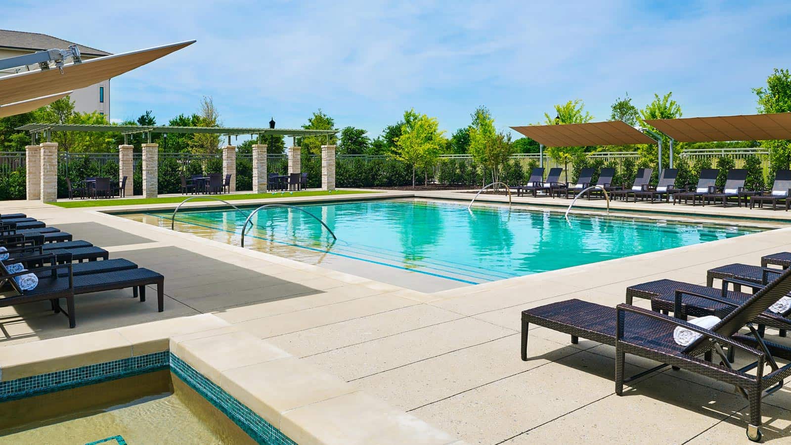 Pool area with lounge chairs and a clear blue sky