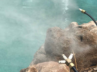 High-pressure water cleaning of rocks with a hose against a turquoise water background