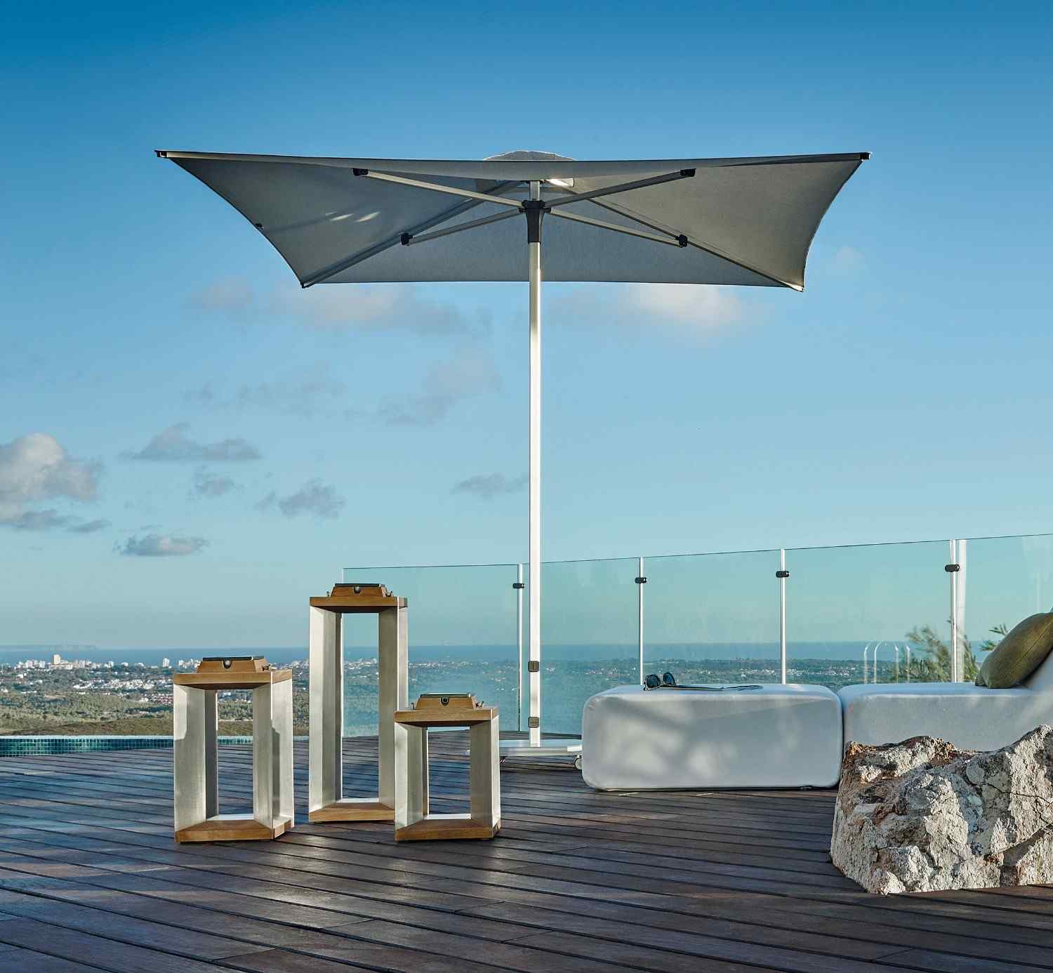 Outdoor patio with umbrella, tables, and view of ocean and city skyline