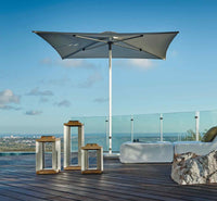 Outdoor patio with umbrella, tables, and view of ocean and city skyline