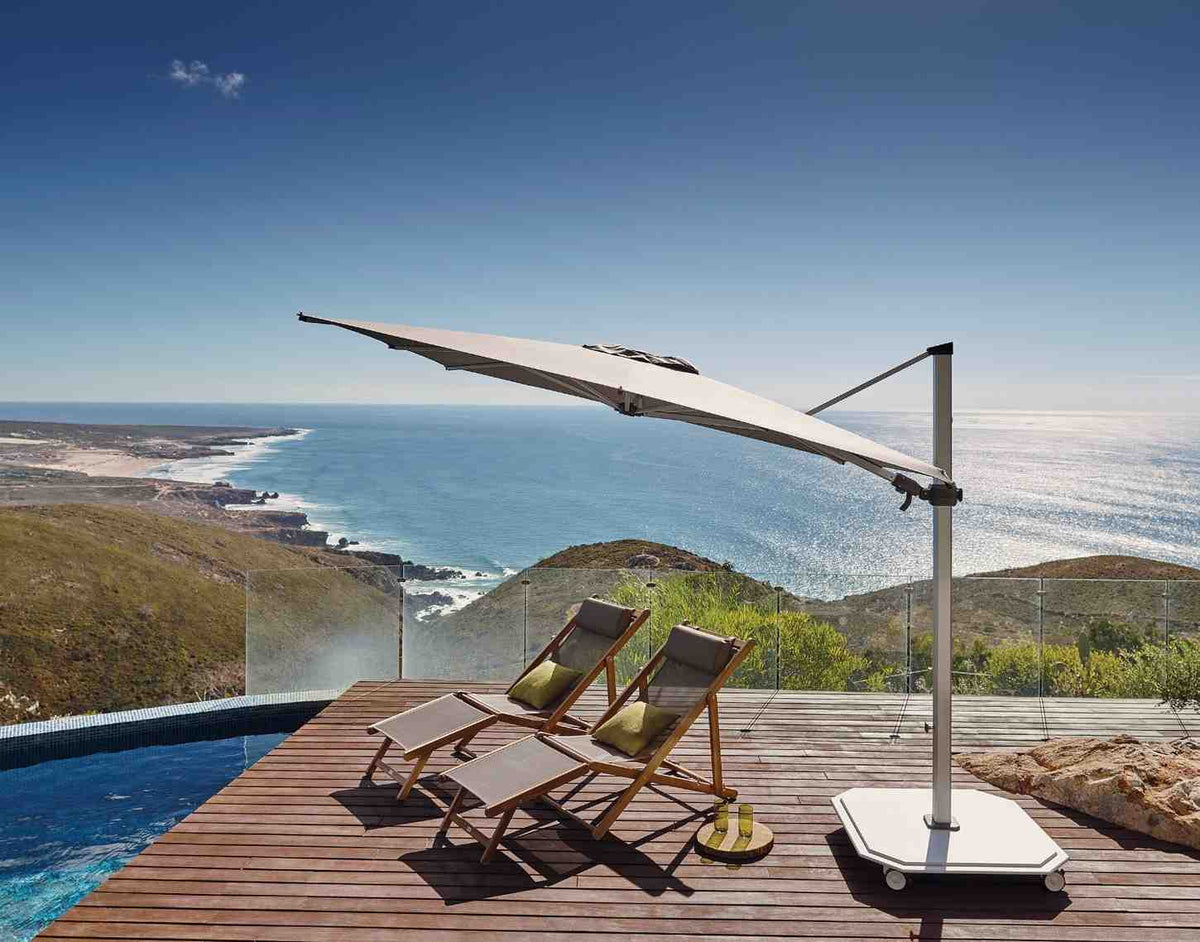 Outdoor pool area with lounge chairs and a large umbrella overlooking a scenic landscape.