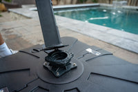 Close-up of a black umbrella base with a pool in the background
