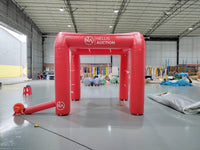 Red inflatable arch with Nellis Auction branding in a warehouse setting.