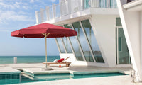 Red umbrella and lounge chair by a pool with ocean view