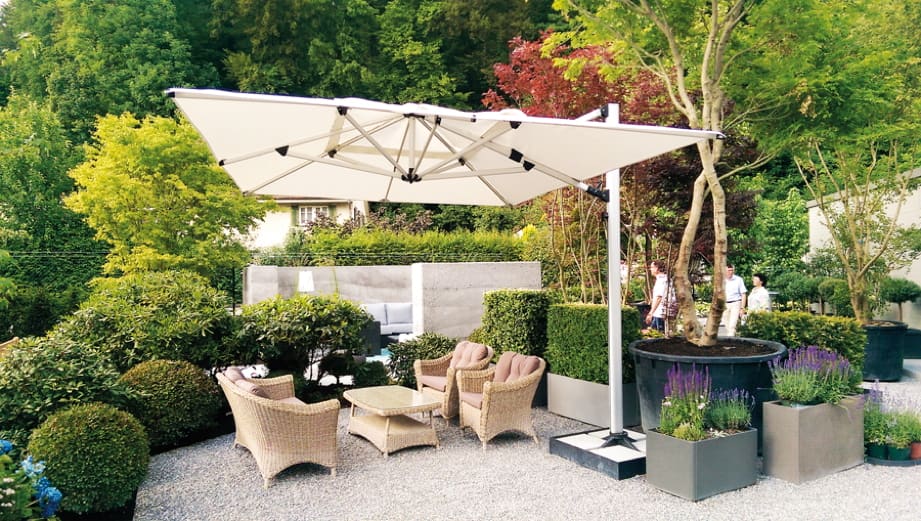 Outdoor patio with wicker furniture, umbrella, and garden plants.