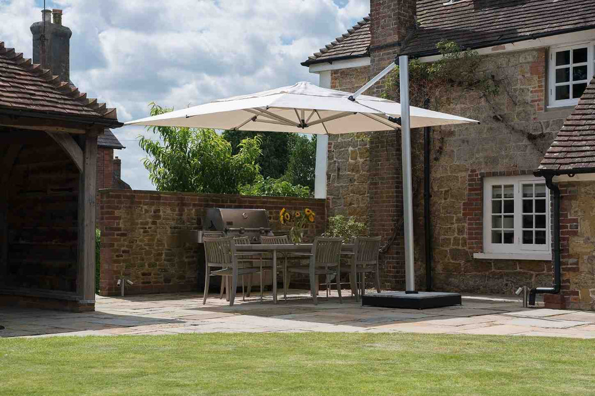 Patio area with a large white umbrella, outdoor furniture, and a stone building.