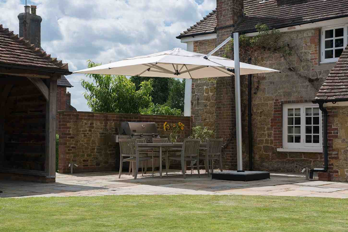 Patio area with a large white umbrella, outdoor furniture, and a stone building.