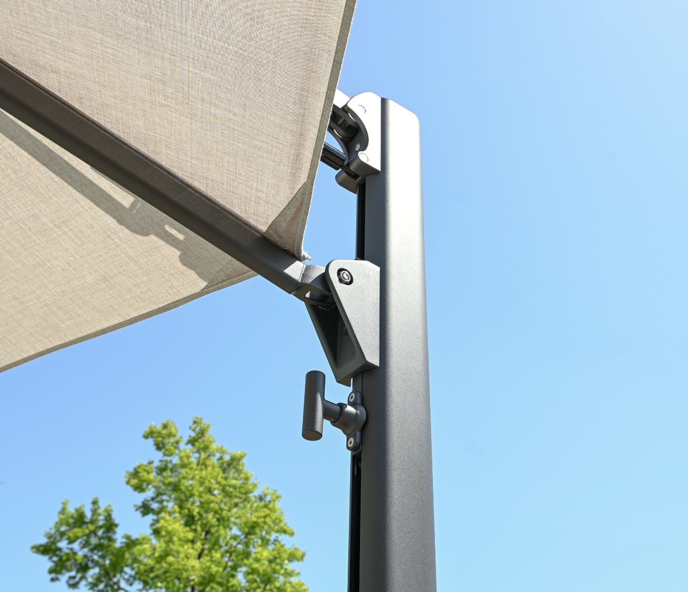 Beige outdoor canopy with metal bracket against a clear blue sky