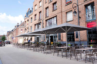 Outdoor seating area with tables and chairs in front of a brick building with a restaurant sign.