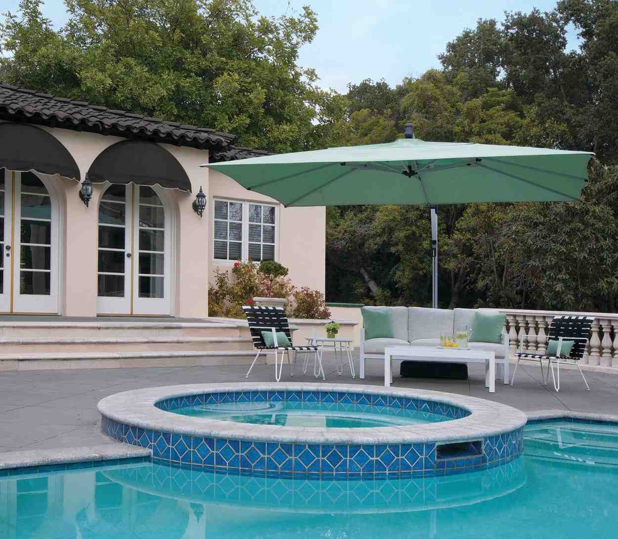 Outdoor setting with a pool, patio furniture, and a large green umbrella.