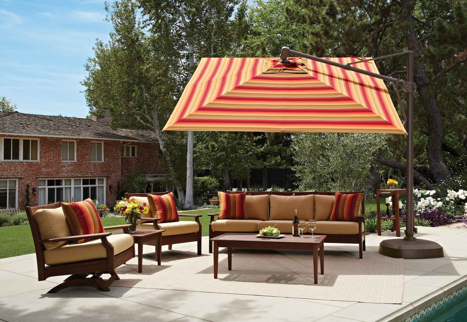 Outdoor patio set with striped umbrella, chairs, and sofa under a clear blue sky.