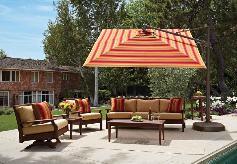 Outdoor patio set with striped umbrella, chairs, and sofa under a clear blue sky.