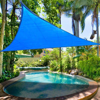 Blue triangular shade sail over a pool with lush greenery in the background