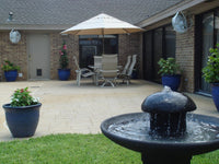 Backyard with patio furniture, umbrella, and water fountain.