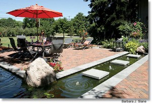 Outdoor patio and water feature shaded by an umbrella.