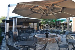 Outdoor restaurant seating with large patio umbrellas providing shade.